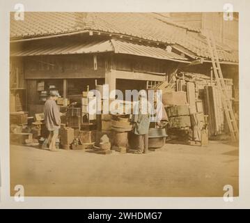 Vue extérieure du magasin au coin de la rue avec des marchandises le long des côtés de la rue et trois personnes, les acheteurs et le marchand....Japon coloré à la main avec aquarelle Photographic Print circa 1870s Banque D'Images