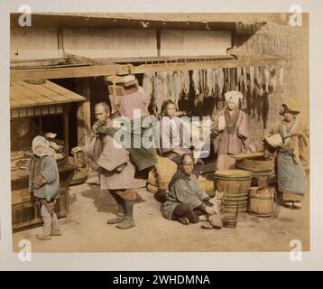 Vue extérieure du marché aux poissons avec plusieurs personnes, acheteurs et marchand, tenant du poisson, également un porteur avec un grand paquet sur son dos, et une femme jouant de l'instrument.... Japon coloré à la main avec aquarelle Photographic Print vers 1870s Banque D'Images