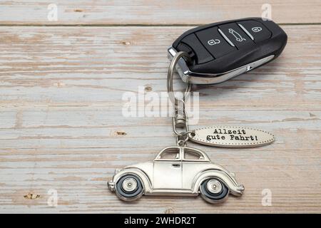 Clé de voiture avec pendentif de clé en métal, inscription 'toujours avoir un bon voyage', fond blanc, image symbolique, nouvelle voiture, Banque D'Images