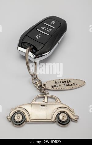 Clé de voiture avec pendentif de clé en métal, inscription 'toujours avoir un bon voyage', fond blanc, image symbolique, nouvelle voiture, Banque D'Images