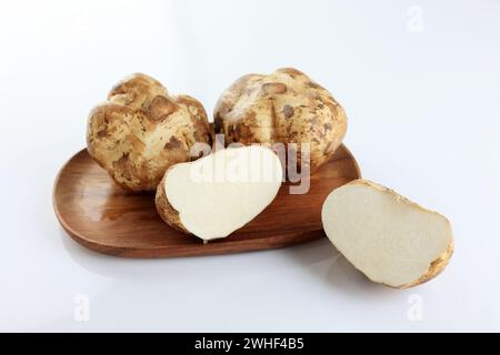 Jicama ou Bengkuang sur plaque en bois, fond blanc Banque D'Images