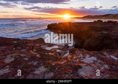 Un coucher de soleil coloré sur des corniches rocheuses le long d'une côte isolée à Forest Caves sur Phillip Island dans le Victoria, Australie. Banque D'Images