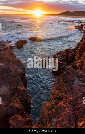 Un coucher de soleil coloré sur des corniches rocheuses le long d'une côte isolée à Forest Caves sur Phillip Island dans le Victoria, Australie. Banque D'Images