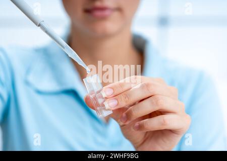 Le scientifique pipette dans une cuvette Banque D'Images