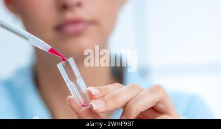 Le scientifique pipette dans une cuvette Banque D'Images