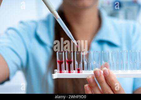 Scientifique pipettant dans des cuvettes Banque D'Images