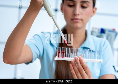 Scientifique pipettant dans des cuvettes Banque D'Images