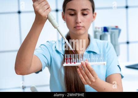 Scientifique pipettant dans des cuvettes Banque D'Images