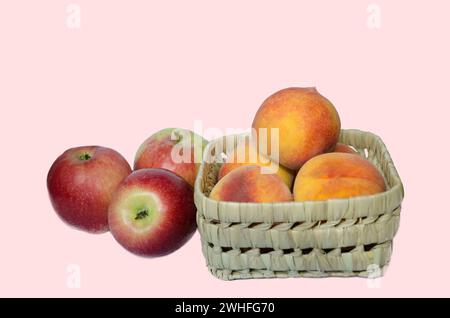 Panier plein de pêches jaunes et de pommes fraîches du jardin bio sur un fond clair Banque D'Images