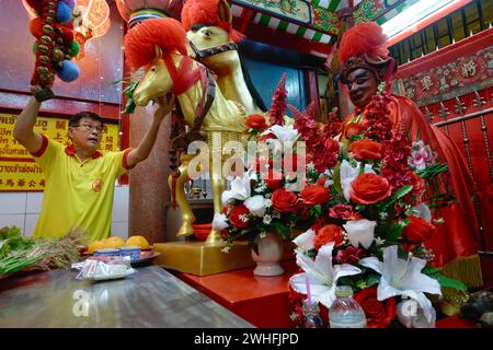 À Sanjao Kuan Teh (ancien temple de Kuan Teh) à Chinatown, Bangkok, Thaïlande, un employé du temple nourrit une statue du célèbre cheval de guerre chinois Chi tu Banque D'Images