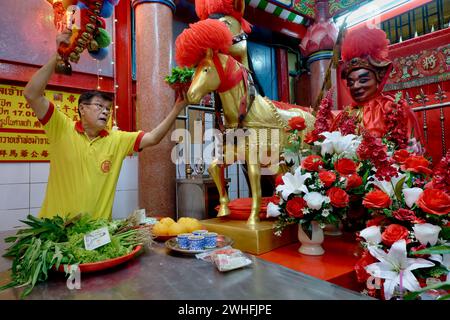 À Sanjao Kuan Teh (ancien temple de Kuan Teh) à Chinatown, Bangkok, Thaïlande, un employé du temple nourrit une statue du célèbre cheval de guerre chinois Chi tu Banque D'Images