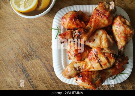 Cuisses de poulet grillées sur une assiette blanche. Arrière-plan rustique Banque D'Images