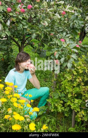 Girlie inspire l'arôme d'une pomme, assis dans le jardin Banque D'Images