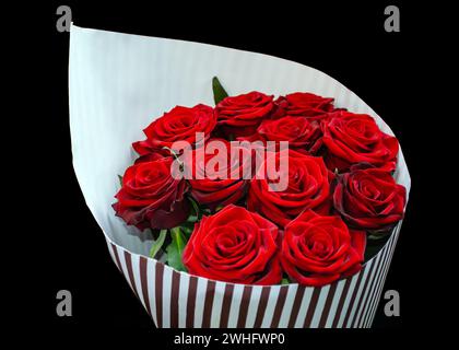 Roses rouges, fleurs naturelles enveloppées dans du papier sur un fond noir Banque D'Images