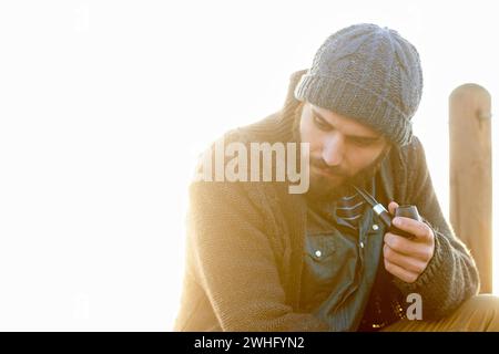 Jeune, homme et fumer une pipe en plein air, penser et fumer habitude le matin au lever du soleil. Mec anglais, dépendance à la nicotine et fumeur rétro pour le calme Banque D'Images