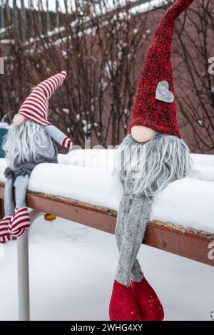 Couple de nains sur le banc dans la neige. Cadeau romantique. Concept d'amitié. Concept de la Saint-Valentin. Gnomes avec coeur et chapeau rouge dans la neige. Banque D'Images