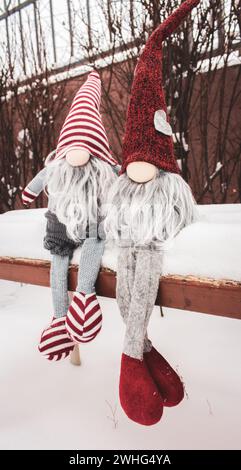 Couple de nains sur le banc dans la neige. Cadeau romantique. Concept d'amitié. Concept de la Saint-Valentin. Gnomes avec coeur et chapeau rouge dans la neige. Banque D'Images