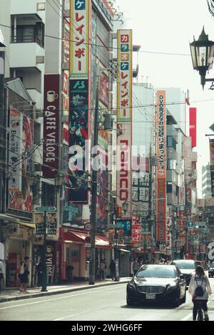 Une scène de rue urbaine animée avec des véhicules, des piétons et une activité animée à Osaka, au Japon. Banque D'Images