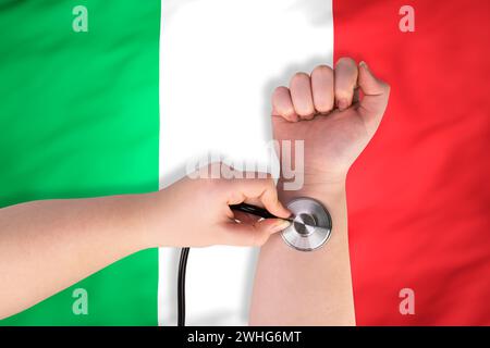 La tête d'un stéthoscope médical au poignet (gros plan) sur fond de drapeau italien. Concept de système de santé italien Banque D'Images