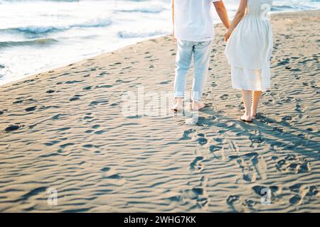 L'homme et la femme se tiennent sur le sable en tenant les mains. Rogné Banque D'Images