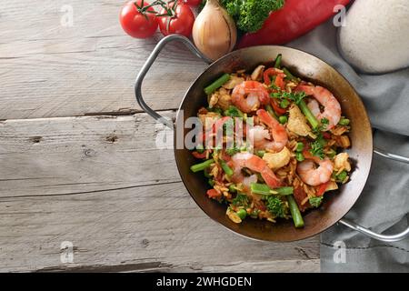 Paella, plat de riz d'Espagne avec des crevettes, du poulet et des légumes dans une poêle plate sur une table en bois rustique, espace copie, ange haut Banque D'Images
