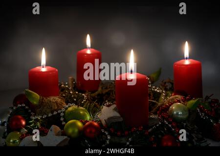 Bougie lumière dans la nuit, partie d'une couronne de l'Avent avec quatre bougies rouges et décoration de Noël sur un fond sombre, co Banque D'Images