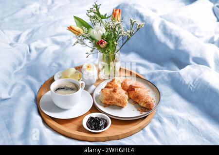Joyeux matin avec petit déjeuner au lit, fleurs, croissant, café et plus sur un plateau sur linge blanc bleu à l'anniversaire, Saint-Valentin o Banque D'Images