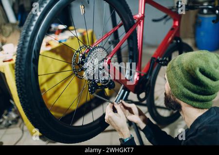 Mécanicien réparateur assemblant des vélos sur mesure installant une chaîne en atelier. Banque D'Images