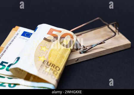 Piège à souris avec papier Euro monnaie devant un fond noir Banque D'Images