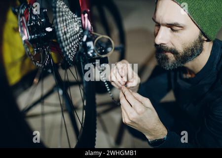 Mécanicien réparateur assemblant des vélos sur mesure installant une chaîne en atelier. Banque D'Images