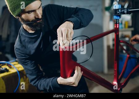 Mécanicien réparateur assemblant les câbles de frein de vélo personnalisés en atelier Banque D'Images