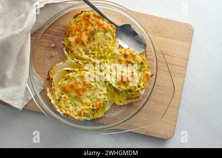 Tranches gratinées de chou chinois ou napa dans une casserole en verre sur une planche de cuisine en bois, plat végétarien créatif, high angl Banque D'Images