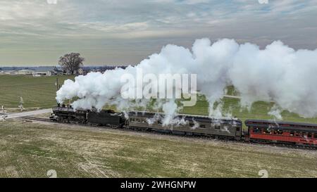 Vue aérienne latérale d'un train de passagers à vapeur approchant, voyageant à travers Open Farmlands Banque D'Images