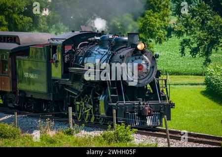 Vue d'une locomotive à vapeur antique restaurée approchant de la fumée soufflante et de la vapeur Banque D'Images