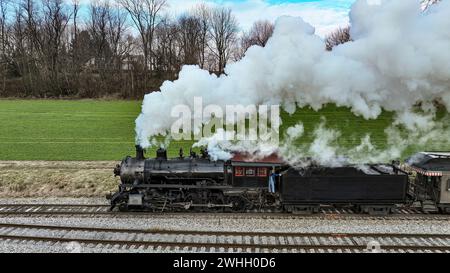 Drone latéral vue d'une locomotive à vapeur approchant Travelling Thru Fields et Meadows Banque D'Images