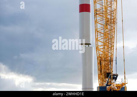 Crane déplace une partie de tour d'une éolienne sur le premier tube guidé par des personnes à l'intérieur, travail de précision dans l'industrie lourde, po Banque D'Images