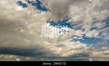 Vue expansive d'Un ciel bleu rempli de nuages de Cumulus blancs projetant des ombres les unes sur les autres sous la lumière du soleil. Banque D'Images