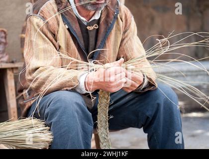 Gros plan de l'homme travaillant en osier pour faire un produit final Banque D'Images