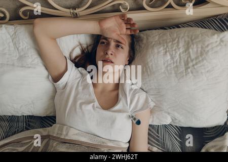 Jeune femme avec mal de tête grippe malade maladie froide à la maison à l'intérieur couché sur le lit. Banque D'Images