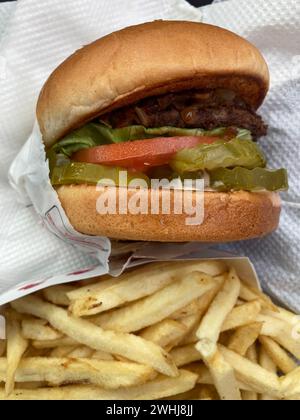Hamburger de restauration rapide avec tomate, laitue, cornichons et accompagnement de frites au drive-in en Californie, aux États-Unis d'Amérique. Repas entièrement américain. Banque D'Images