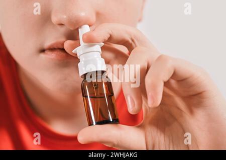 Blond Boy goutte des gouttes de nez du nez qui coule. Traitement des rhumes et rhinites allergiques. Mise au point sélective Banque D'Images