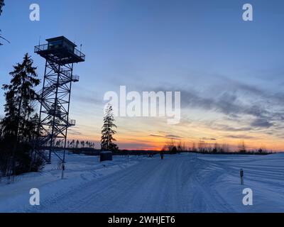 Tapa, Estonie. 10 février 2024. Coucher de soleil sur le terrain d'entraînement militaire enneigé. Au cours d'un exercice hivernal en Estonie, les troupes de l'OTAN s'entraînent pour protéger et défendre le flanc est de l'OTAN dans des conditions hivernales froides. Les forces armées de France et de Grande-Bretagne participent également au 1er exercice, qui se déroule du 15 février jusqu’à la fin de l’année. Crédit : Alexander Welscher/dpa/Alamy Live News Banque D'Images