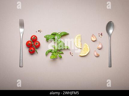 Composition avec branche de tomates cerises fraîches, branche de basilic, gousses d'ail, quartiers de citron, cuillère de cuisine et fourchette sur minimalis Banque D'Images