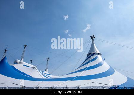grande tente de cirque bleue et blanche sous ciel ensoleillé Banque D'Images