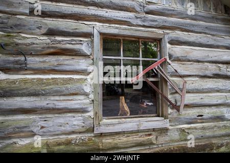 Façade latérale d'une ferme en rondins et fenêtre avec vieille scie suspendue, Ottawa, Canada Banque D'Images