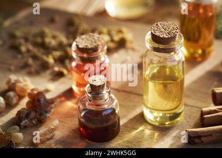 Bouteilles transparentes d'huiles essentielles d'aromathérapie avec résine d'encens, bâtonnets de cannelle et herbes séchées Banque D'Images