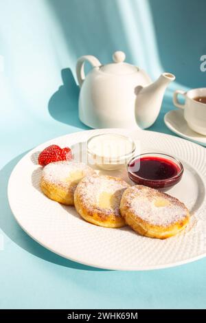 Profitez d'un petit déjeuner sain avec des crêpes moelleuses au fromage cottage garnies de confiture, de fraises fraîches et d'une cuillère de crème sure. Dynamisez votre esprit de journée Banque D'Images
