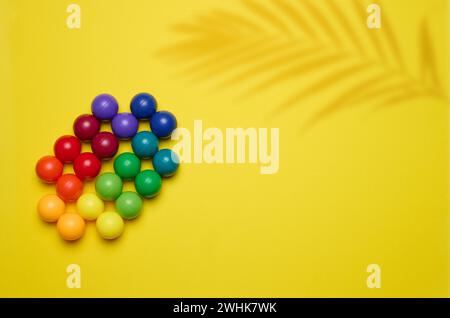 Fond abstrait avec des boules en plastique multicolores sur un fond jaune, une scène pour la démonstration de cosmétiques et de prod Banque D'Images