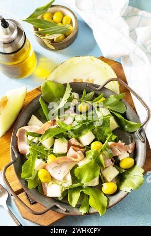 Apéritif traditionnel espagnol et italien. Salade méditerranéenne d'été avec melon, bacon, olives, fromage blanc et roquette sur blu Banque D'Images