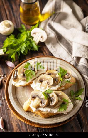 Bruschetta maison aux champignons. Sandwich grillé à partir de pain baguettes avec fromage à pâte molle et champignons grillés sur rusti en bois Banque D'Images